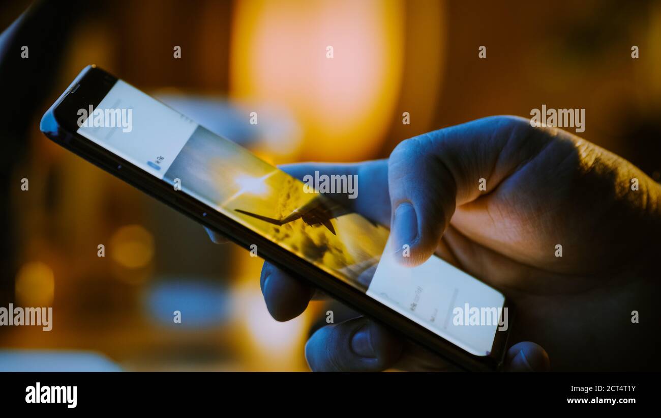 Nahaufnahme Makro: Person hält und mit Smartphone, Browsing durch Bilder auf Social Network Wall. Fingerscrolling Social Media App Feed: Reisen Stockfoto