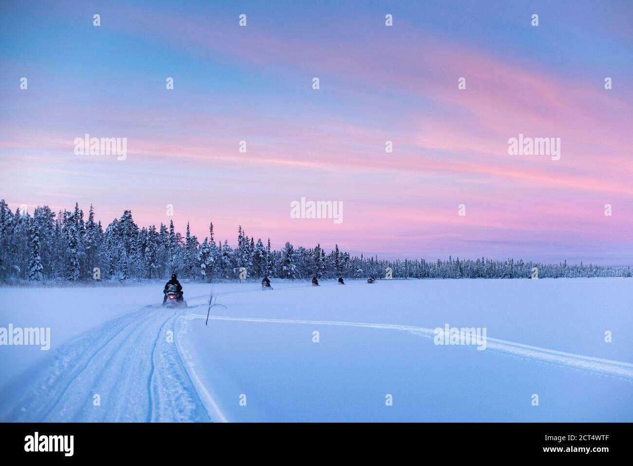 Motorschlittenfahrt auf dem gefrorenen See bei Sonnenuntergang in Torassieppi, Lappland, Finnland Stockfoto