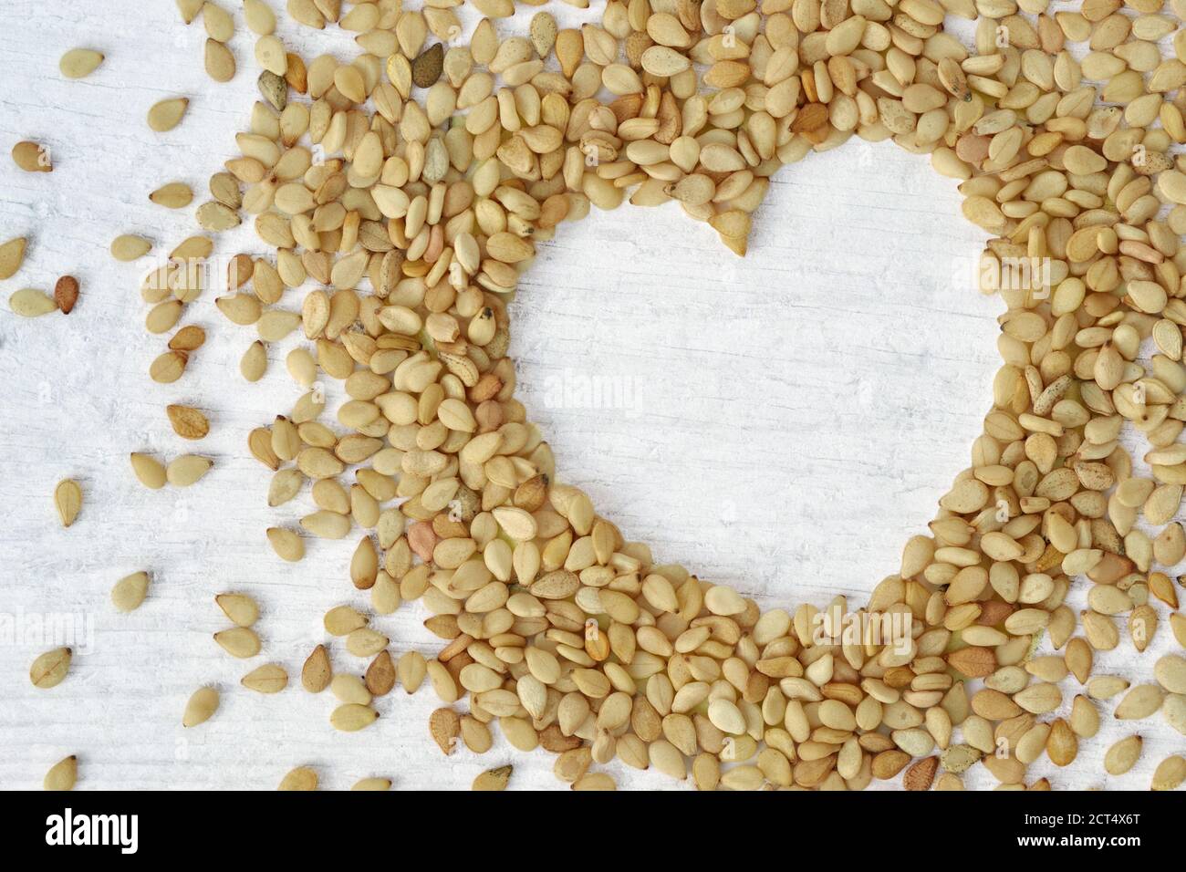 Sesamsamen in Herzform auf Holzhintergrund - Sesamsamen sind gut für Herz gesund Stockfoto