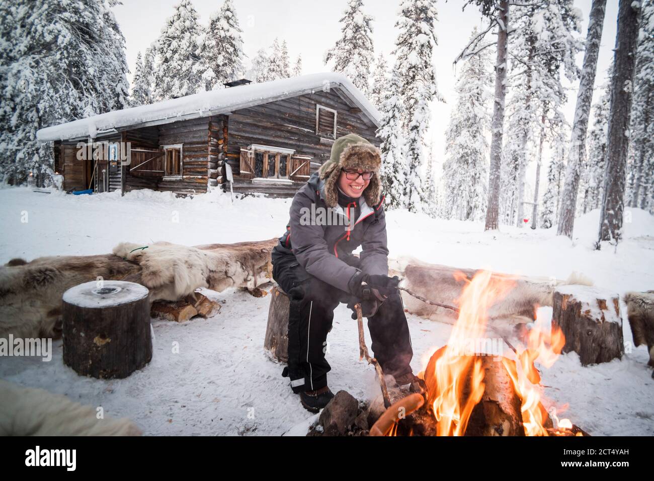 Person saß an einem Lagerfeuer und wärmte sich an einem eisigen kalten Wintertag am Polarkreis in Lappland, Finnland Stockfoto