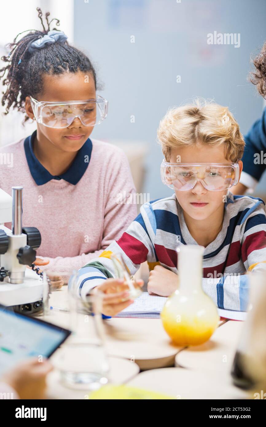 Grundschule Wissenschaft Klassenzimmer: Cute Little Boy in Sicherheitsbrillen mischt Chemikalien in Bechergläser. Kinder lernen Chemie Wissenschaft mit Interesse Stockfoto