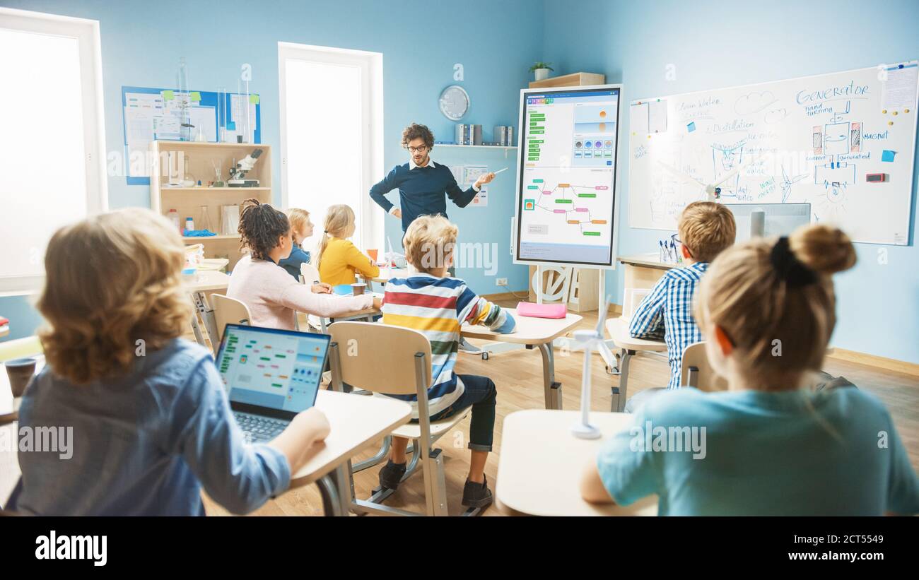 Grundschulinformatik-Lehrer verwendet interaktive digitale Whiteboard zu Zeigen Sie Programmierlogiken zu einem Klassenzimmer voller Smart Diverse Stockfoto