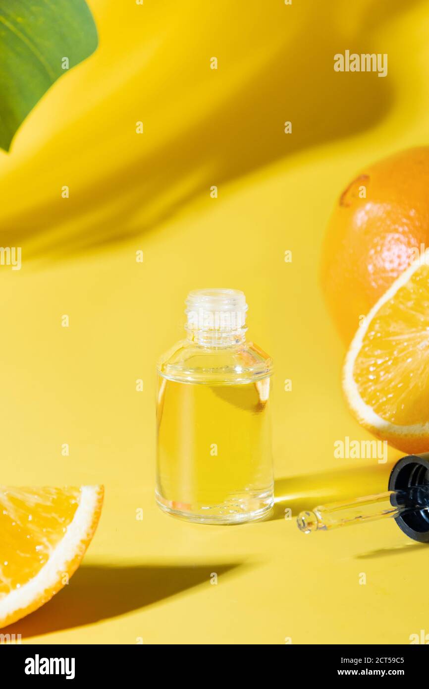 Kosmetisches Öl, Hyaluronsäure oder Essenz auf gelbem Hintergrund. Anti-Age-Pflege. Nahaufnahme. Vertikales Format. Stockfoto