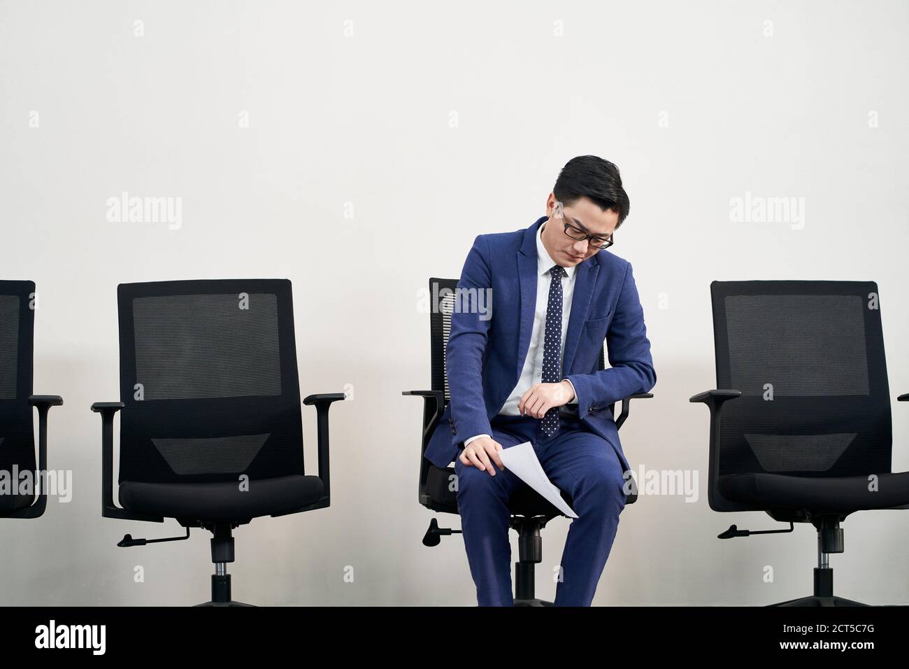 Junge asiatische männliche Arbeitssuchende sitzen in Stuhl mit Kopf Down scheint frustriert und besiegt zu sein Stockfoto