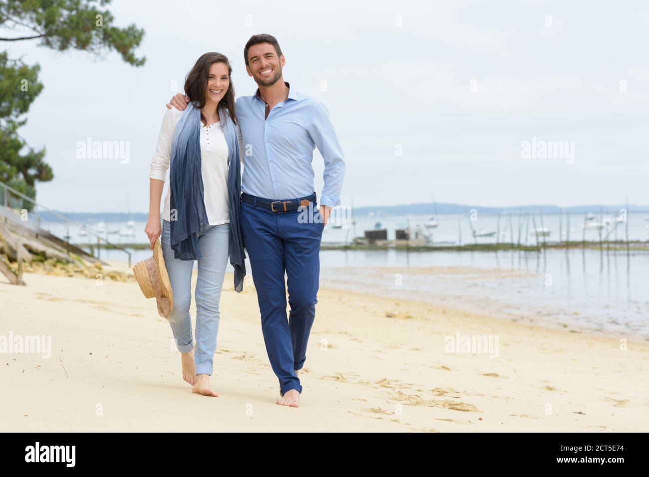 Paar in legerer Kleidung, die am Strand spazieren gehen Stockfoto