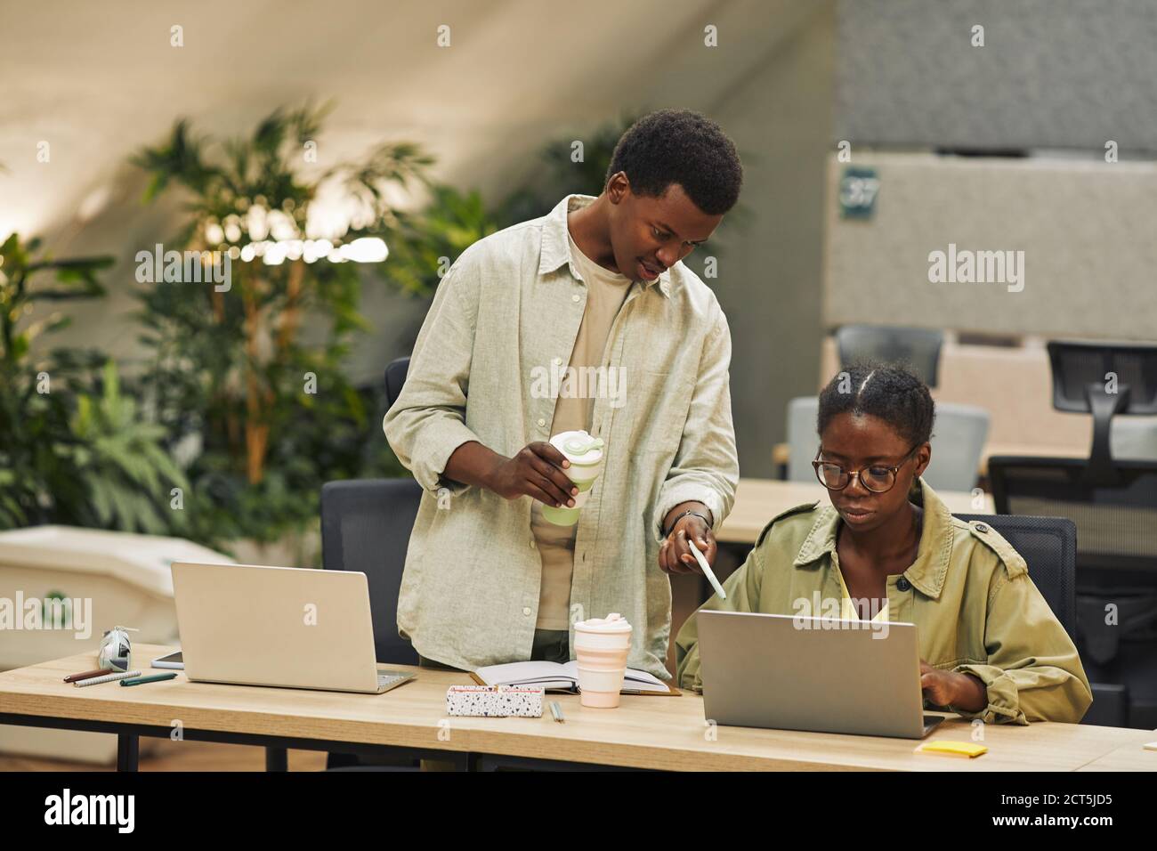 Portrait von zwei afroamerikanischen Menschen arbeiten in modernen Open Space Büro, konzentrieren sich auf junge Mann instruiert Kollegen und zeigt auf Laptop-Bildschirm , Kopierer Raum Stockfoto Portrait von zwei afroamerikanischen Menschen arbeiten in modernen Open Space Büro, konzentrieren sich auf junge Mann instruiert Kollegen und zeigt auf Laptop-Bildschirm , Kopierer Raum Stockfoto