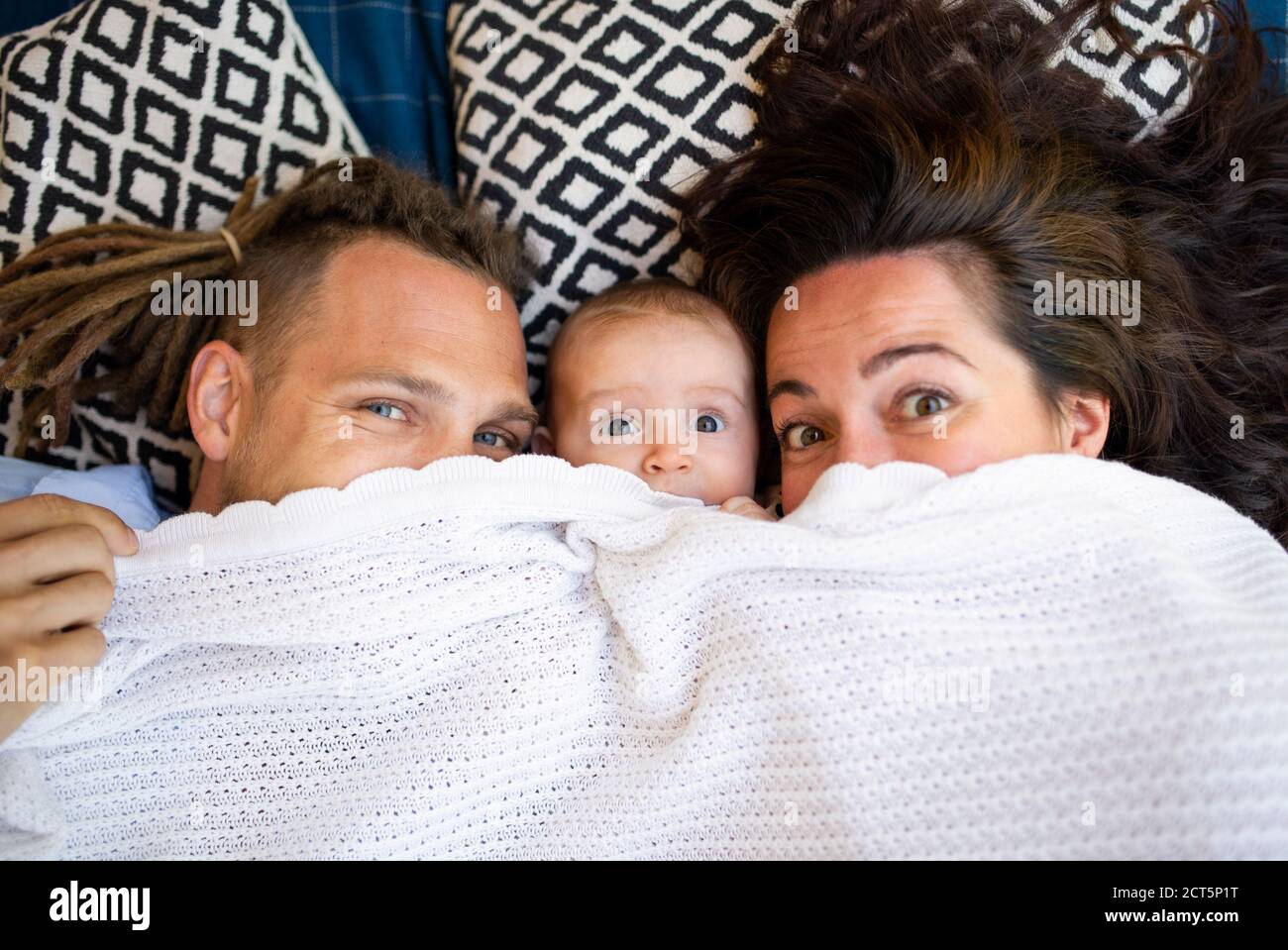 Junges Paar mit Baby Tochter unter Decke ruhen, Blick auf die Kamera. Stockfoto