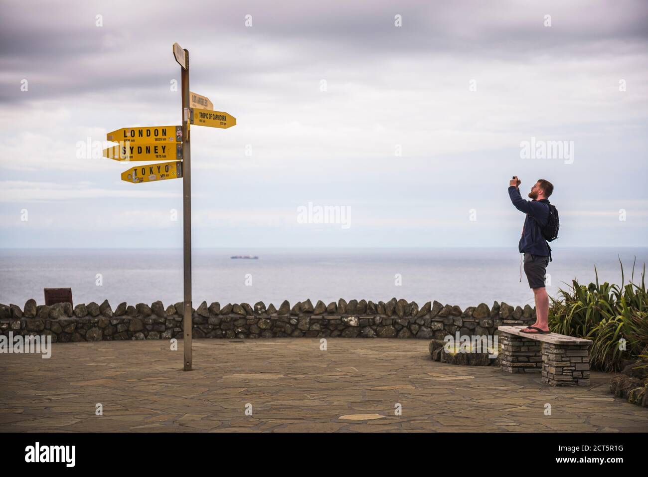 Touristen fotografieren die Stadt Entfernungen Zeichen am Cape Reinga Leuchtturm, Northland, Neuseeland Stockfoto