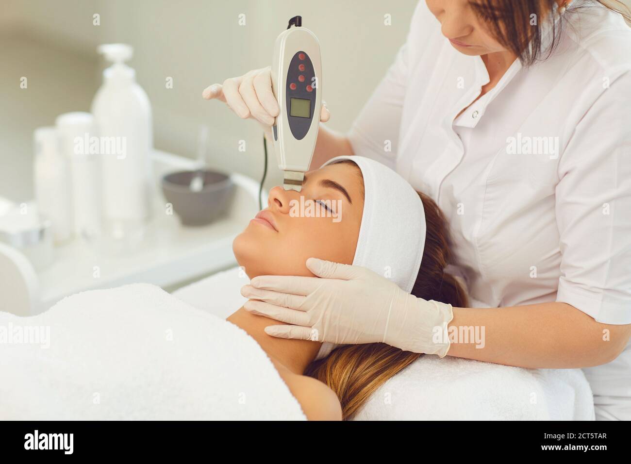 Frau Dermatologe macht Ultraschall-Gerät Gesichtsreinigung für junge Frau Stockfoto