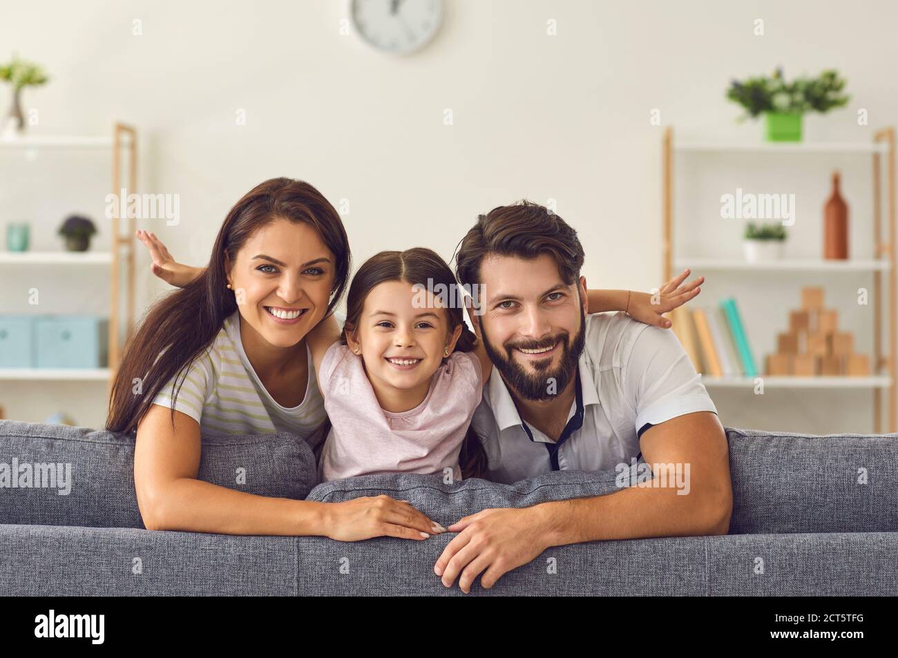 Fröhliche lächelnde Familie sitzt auf dem Sofa zusammen und schaut zu Kamera zu Hause Stockfoto