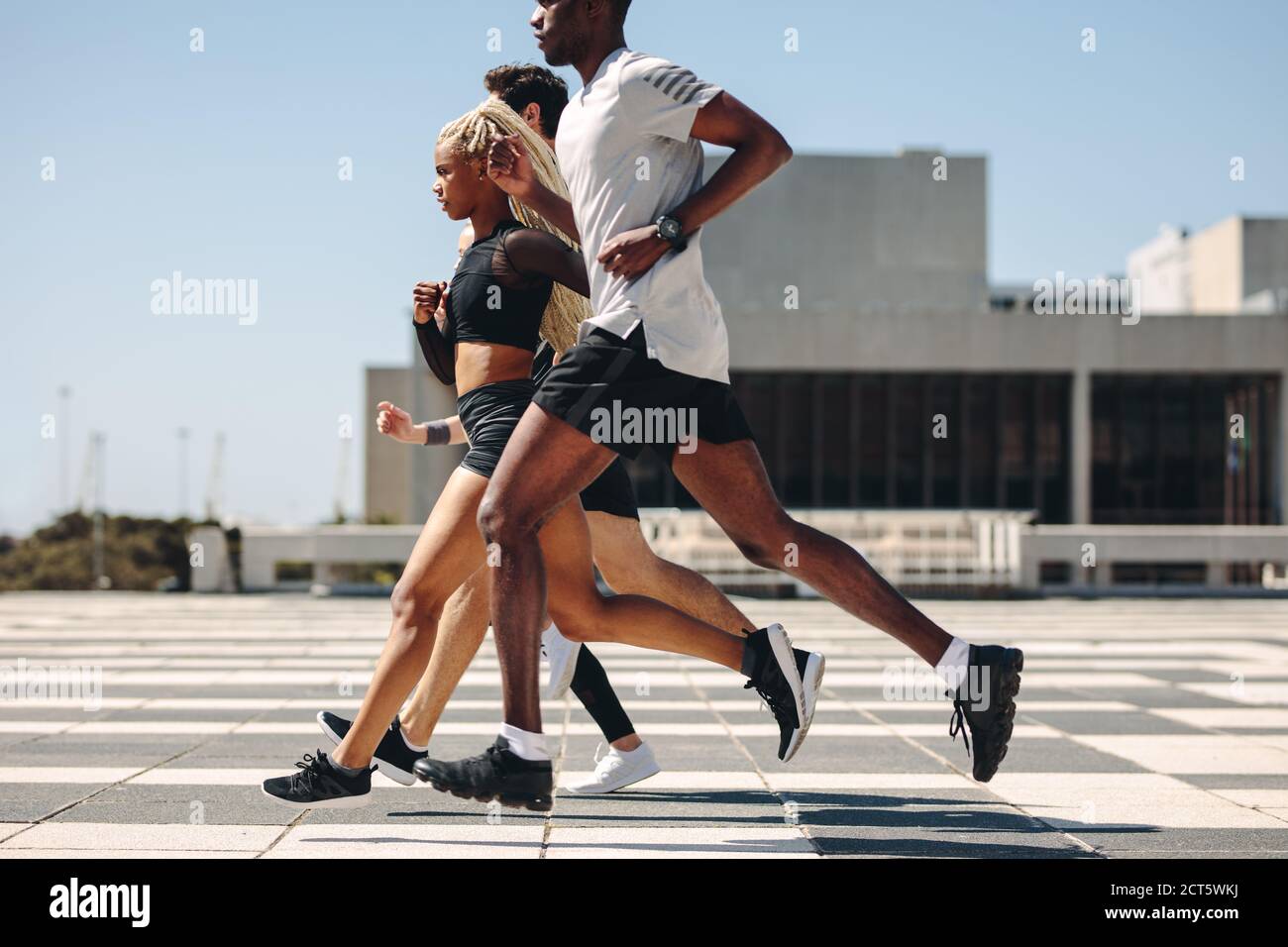 Eine Gruppe von Männern und Frauen, die in der Stadt zusammenlaufen. Multirassische Straßenläufer trainieren in der Stadt. Stockfoto