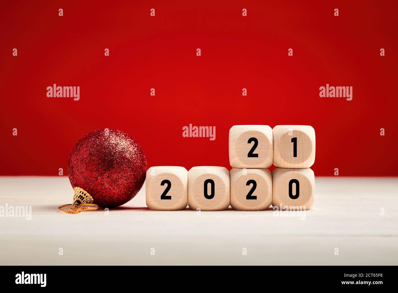 Neujahr-Konzept mit Holzblöcken mit dem Jahr 2020 und 2021 Zahlen ändern sich auf rotem Hintergrund mit einem Weihnachtsschmuck. Stockfoto