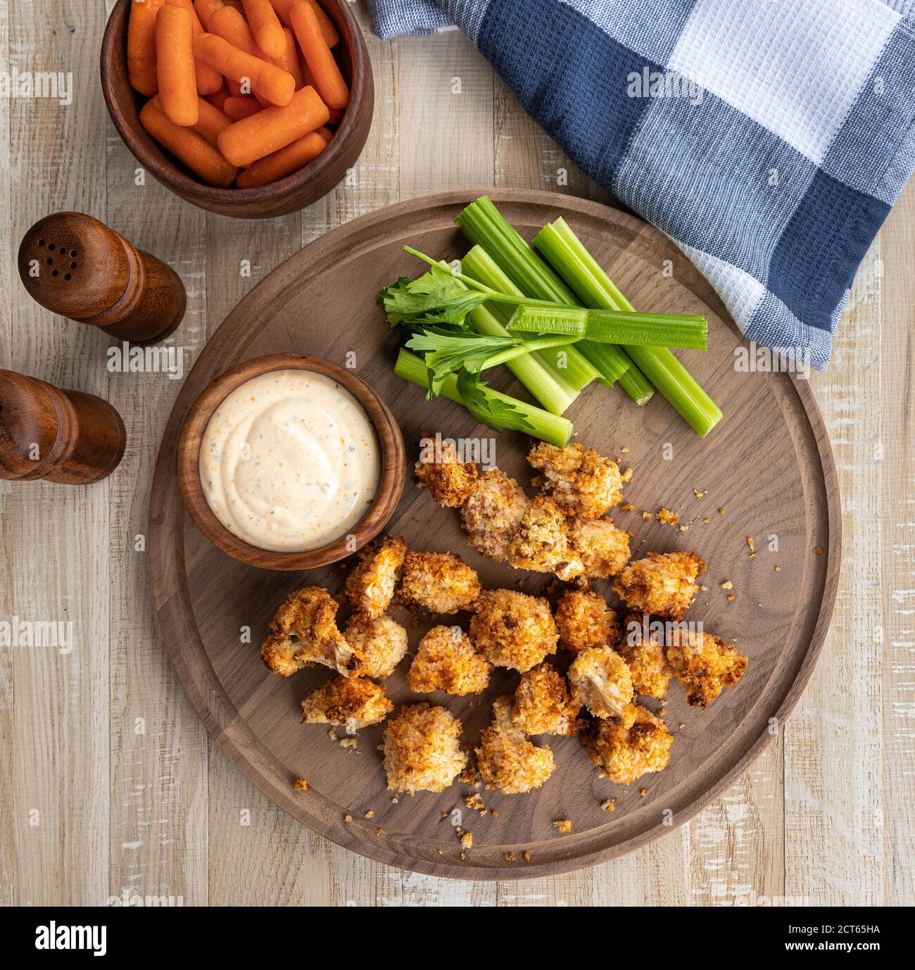 Knusprige Luft gebratene Blumenkohlröschen und Ranch Dip mit Karotten und Sellerie auf einem Holztablett. Blick von oben Stockfoto