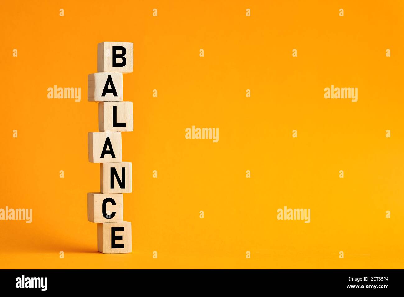 Das Wort Balance auf gestapelten Holzwürfeln mit gelbem Hintergrund. Balance im Lebens-, Arbeits- oder Geschäftskonzept. Stockfoto