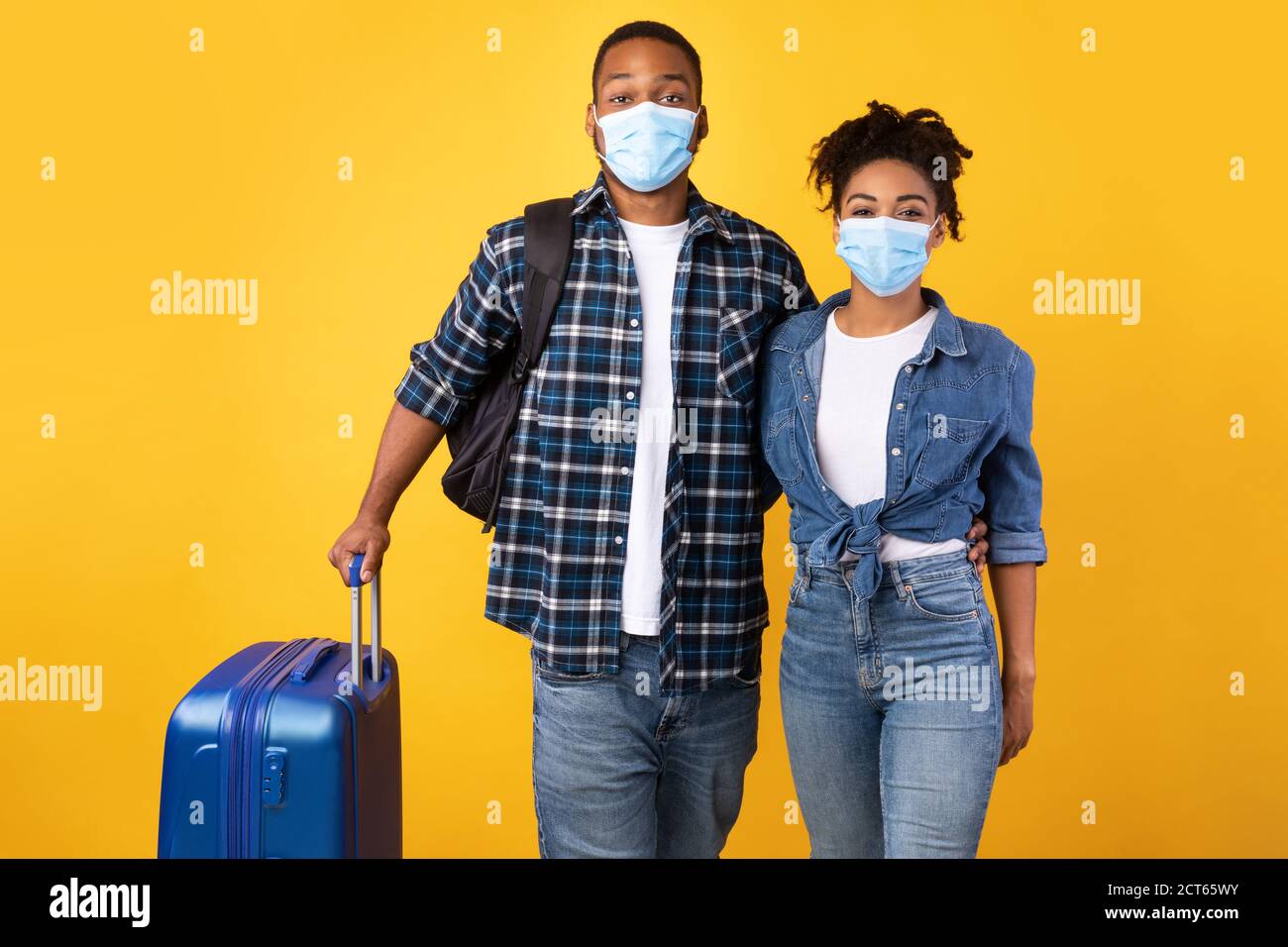 Schwarzes Paar Trägt Masken Stehen Mit Koffer Auf Gelbem Hintergrund Stockfoto