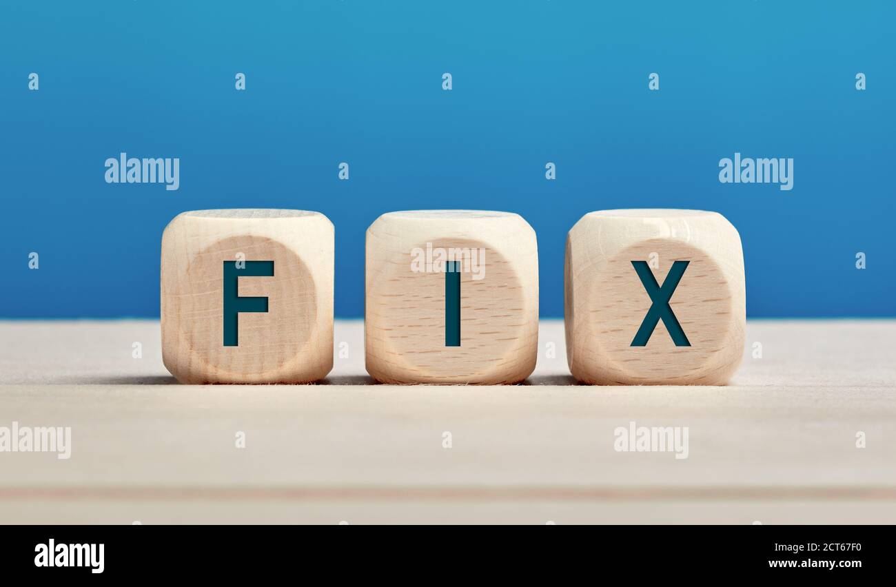 Das Wort fix auf Holzwürfel vor blauem Hintergrund. Reparatur-, Reparatur- oder Lösungskonzept. Stockfoto