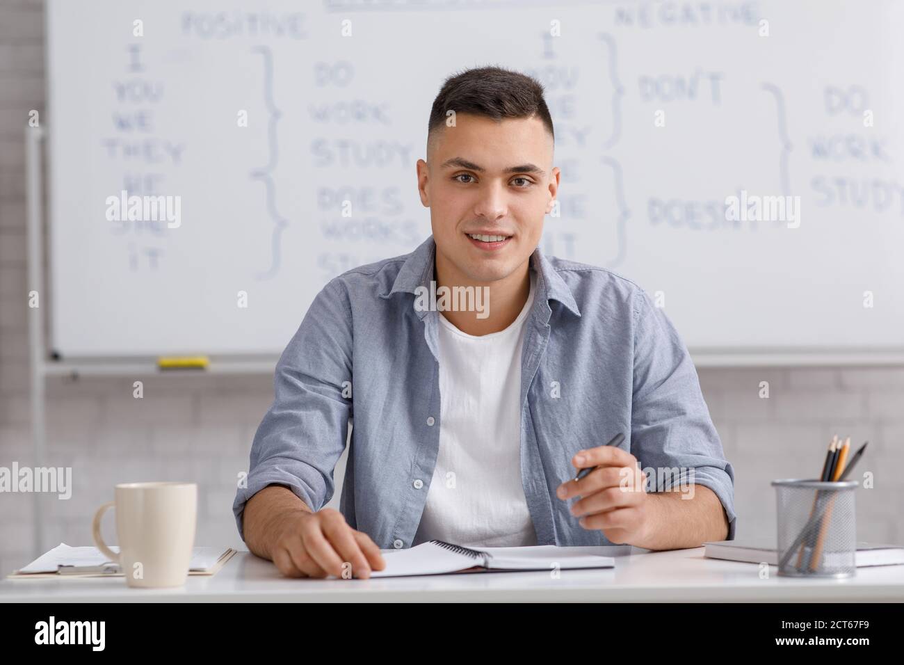 Arbeitsplatz, Arbeit von zu Hause und unterrichten englisch mit Tutor. Attraktiver Kerl in Casual, Gespräche mit Studenten, Blick auf Webcam, sitzen am Tisch Stockfoto