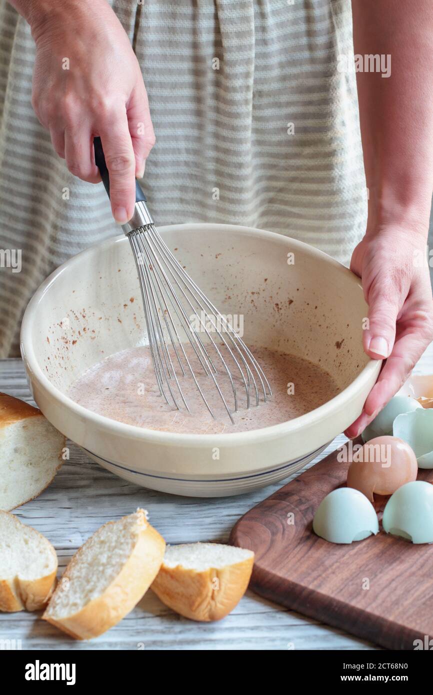 Frauenhände bereiten French Toast Teig mit Bauernhof frische Bio-Eier und ein Laib Brot in der Nähe. Stockfoto