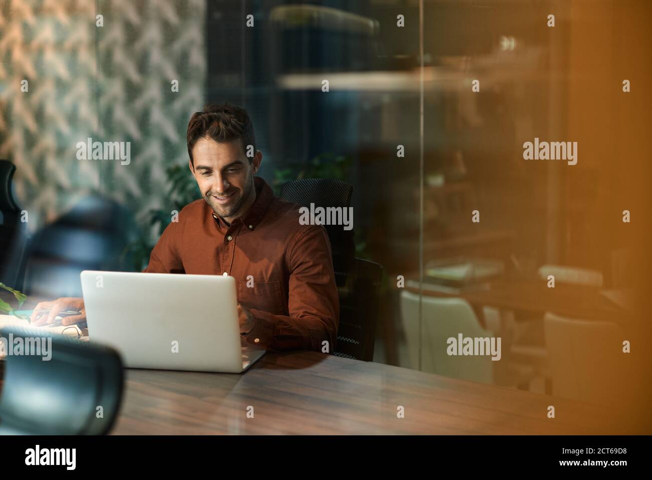 Geschäftsmann, der außerhalb der Geschäftszeiten in einem Büro an einem Laptop arbeitet Stockfoto