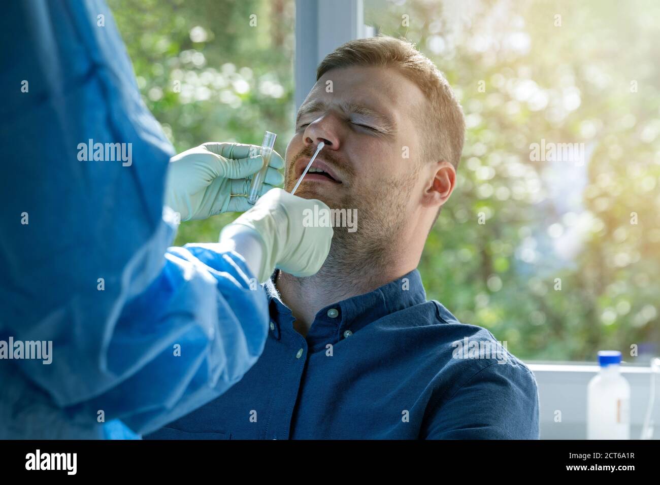 Coronavirus Nasenabstrich Test - Laborarbeiter unter einem Schleim Probe aus der Nase des männlichen Patienten Stockfoto