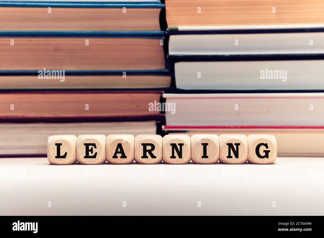 Das Wort Lernen auf Holzwürfel vor gestapelten Büchern Hintergrund. Bildung, Lesen und Lernen Konzept. Stockfoto