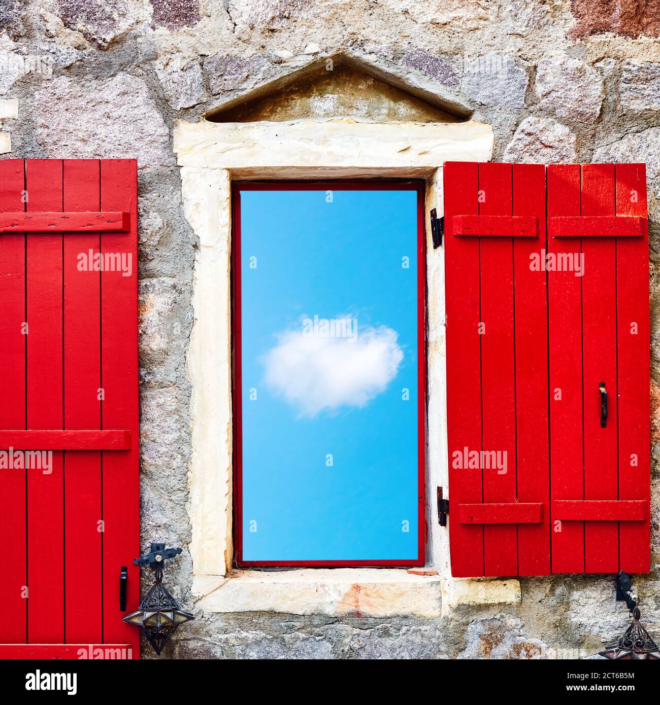 Fenster an einer Steinmauer mit Blick auf den blauen Himmel und die Wolken. Fantasie, Träumen, Freiheit oder Inspirationskonzept. Stockfoto