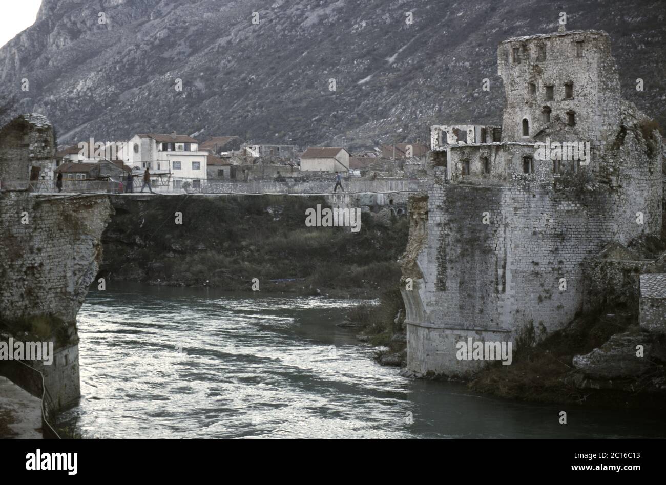 10. Dezember 1995 während des Krieges in Bosnien: Die Menschen überqueren eine Seilbrücke, die die zerstörte Stari Most (Alte Brücke) ersetzt, über den Fluss Neretva in Mostar. Stockfoto