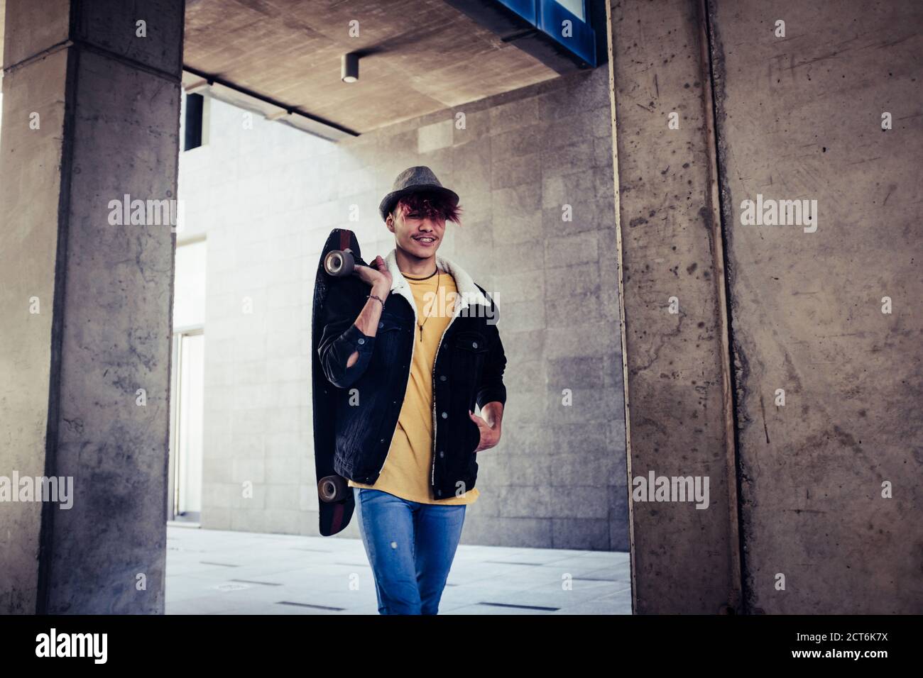 Trendige Alternative junge männliche Teenager gehen in der Stadt mit Urban graue Wand im Hintergrund und Skateboard - Diversity-Konzept Menschen leben mit te Stockfoto