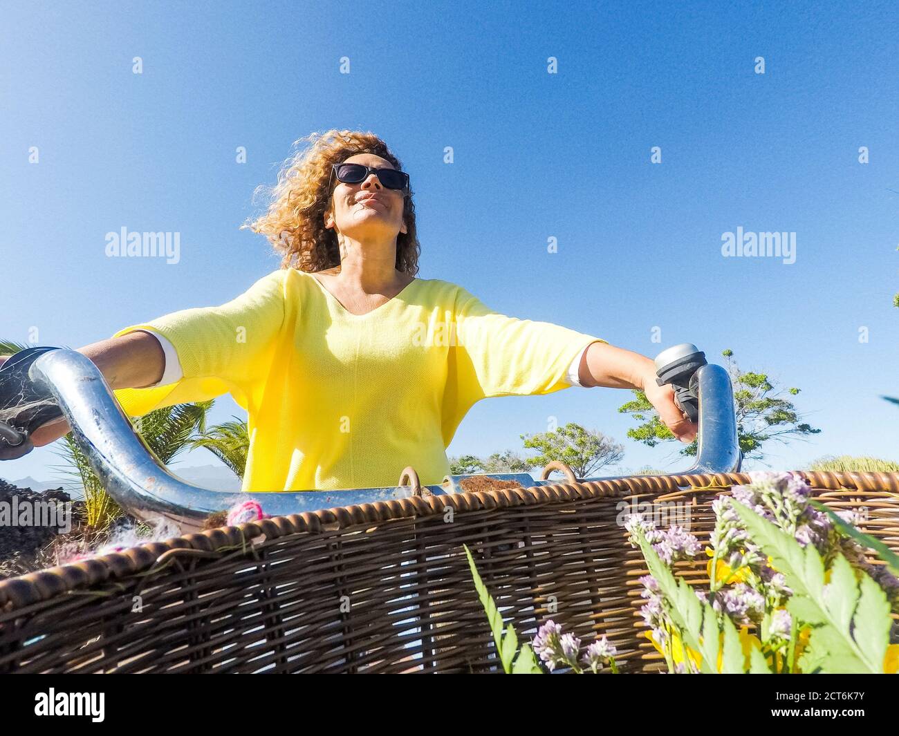 Pov der fröhlichen erwachsenen jungen kaukasischen Frau mit lang glücklich Blonde lockiges Haar fahren Sie das Fahrrad in Outdoor-Freizeitaktivitäten - farbige Porträt von Menschen Stockfoto