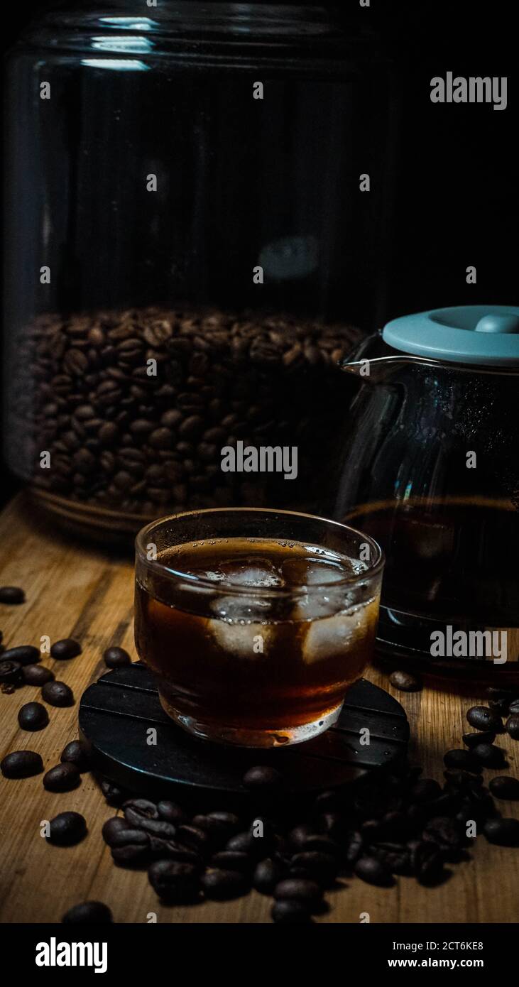 Schwarzer Eiskaffee im Glas und Kaffeebohnen Stockfoto