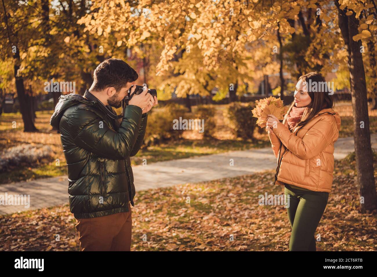 Foto von professionellen Fotografen Kerl nehmen Foto hübsche Mädchen halten Ahorn orange Blätter im Herbst september Wald Stockfoto