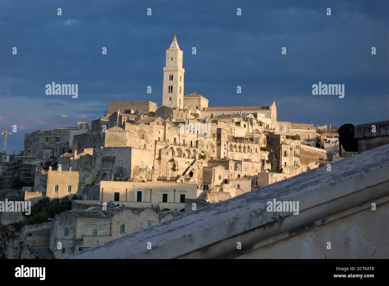 Panoramablick auf Matera mit einem Steingeländer im Vordergrund Und die Kathedrale und Häuser im Hintergrund in Abenduntergang Leicht Stockfoto