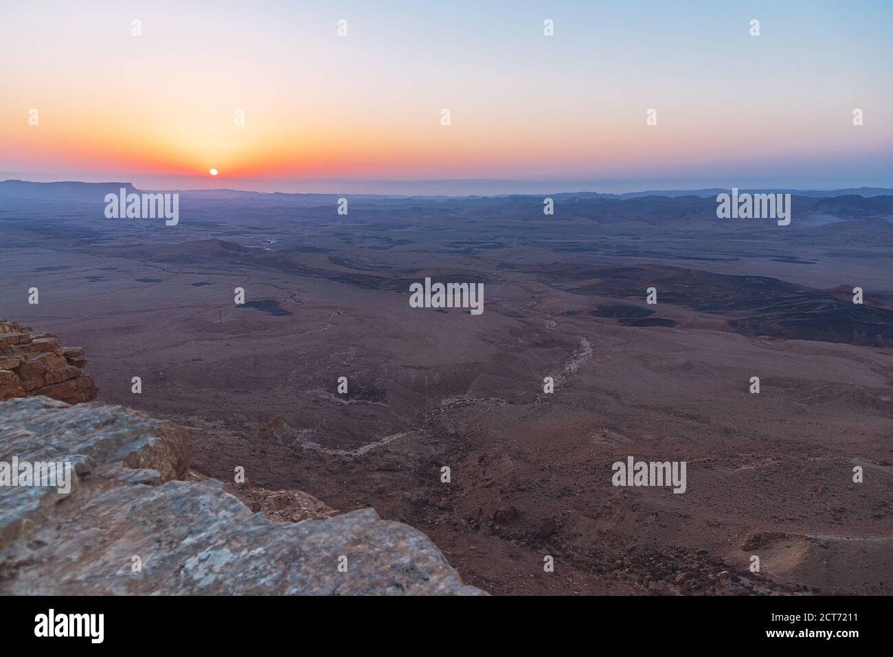 Ein flammender wolkenloser Sonnenaufgang, der die Weite und Geologie von zeigt Der Krater makhesh ramon in der negev-Wüste in israel Stockfoto