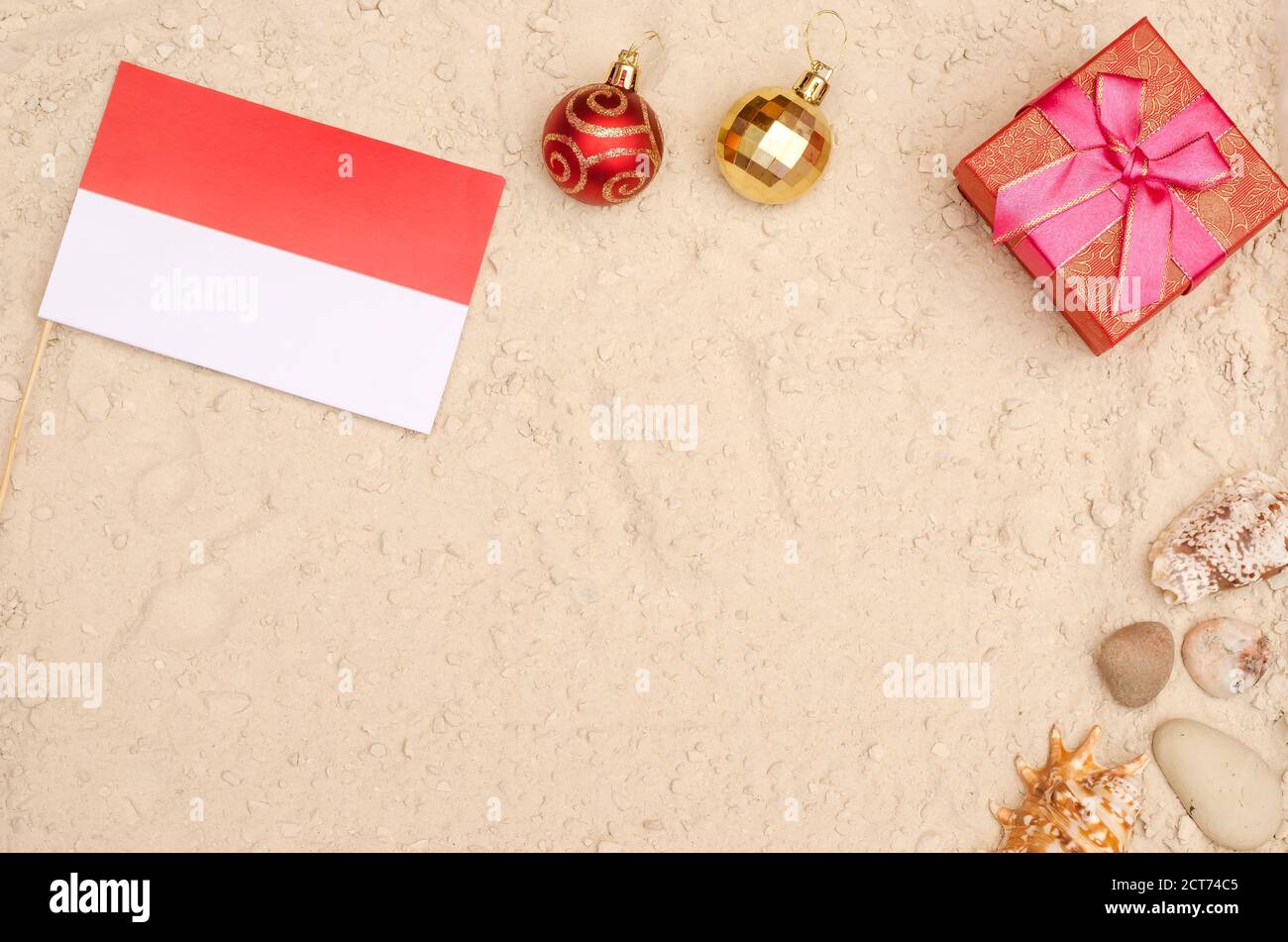 Neujahr und Weihnachtsferien in Monaco. Monaco Flagge am Strand mit einem Geschenk mit Kopierplatz Stockfoto
