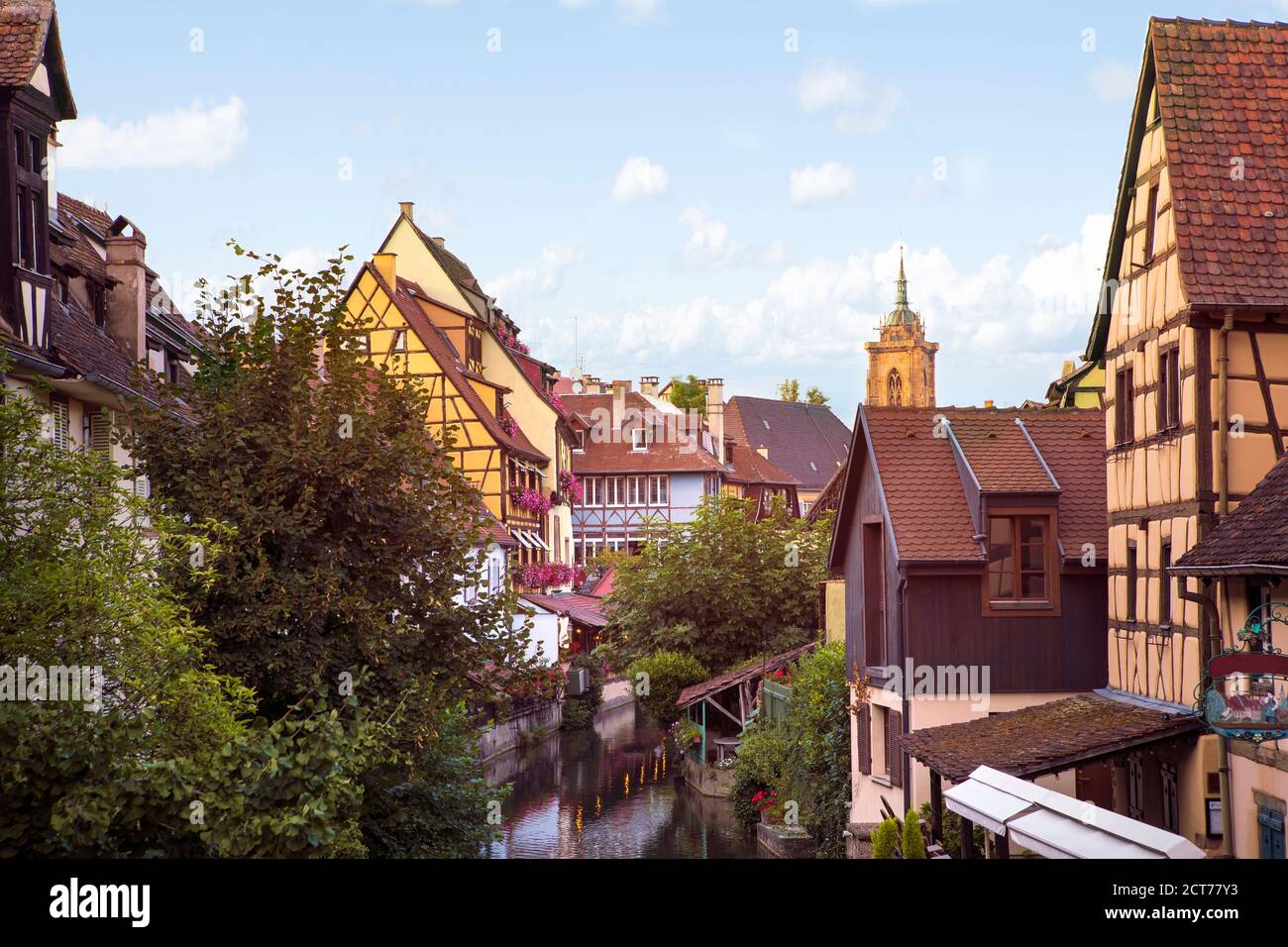 Kleines Venedig in Colmar. Berühmtes Wahrzeichen, romantisches Dorf mit Fachwerkhäusern am Ufer des Kanals, Kirchturm im Hintergrund. Summert Stockfoto