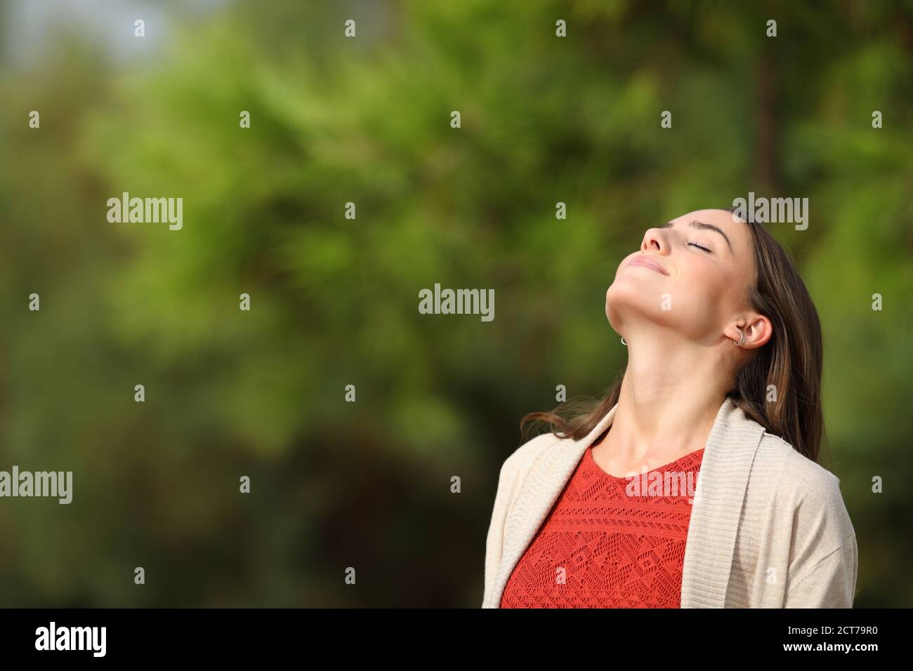 Entspannte Frau atmen frische Luft stehen in einem Park ein Sonniger Tag mit grünem Hintergrund Stockfoto