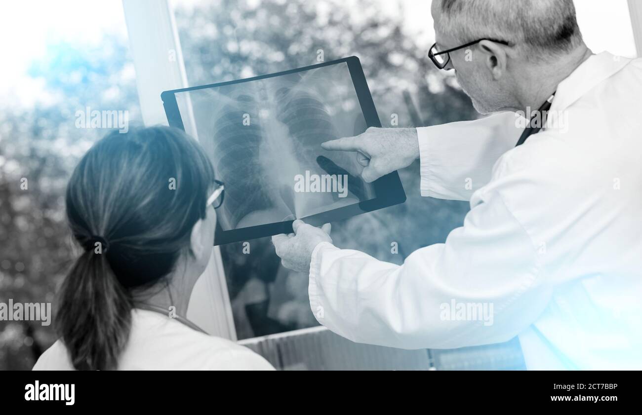 Zwei Ärzte untersuchen Röntgenbericht in der Arztpraxis; schwarz-weiß Stockfoto