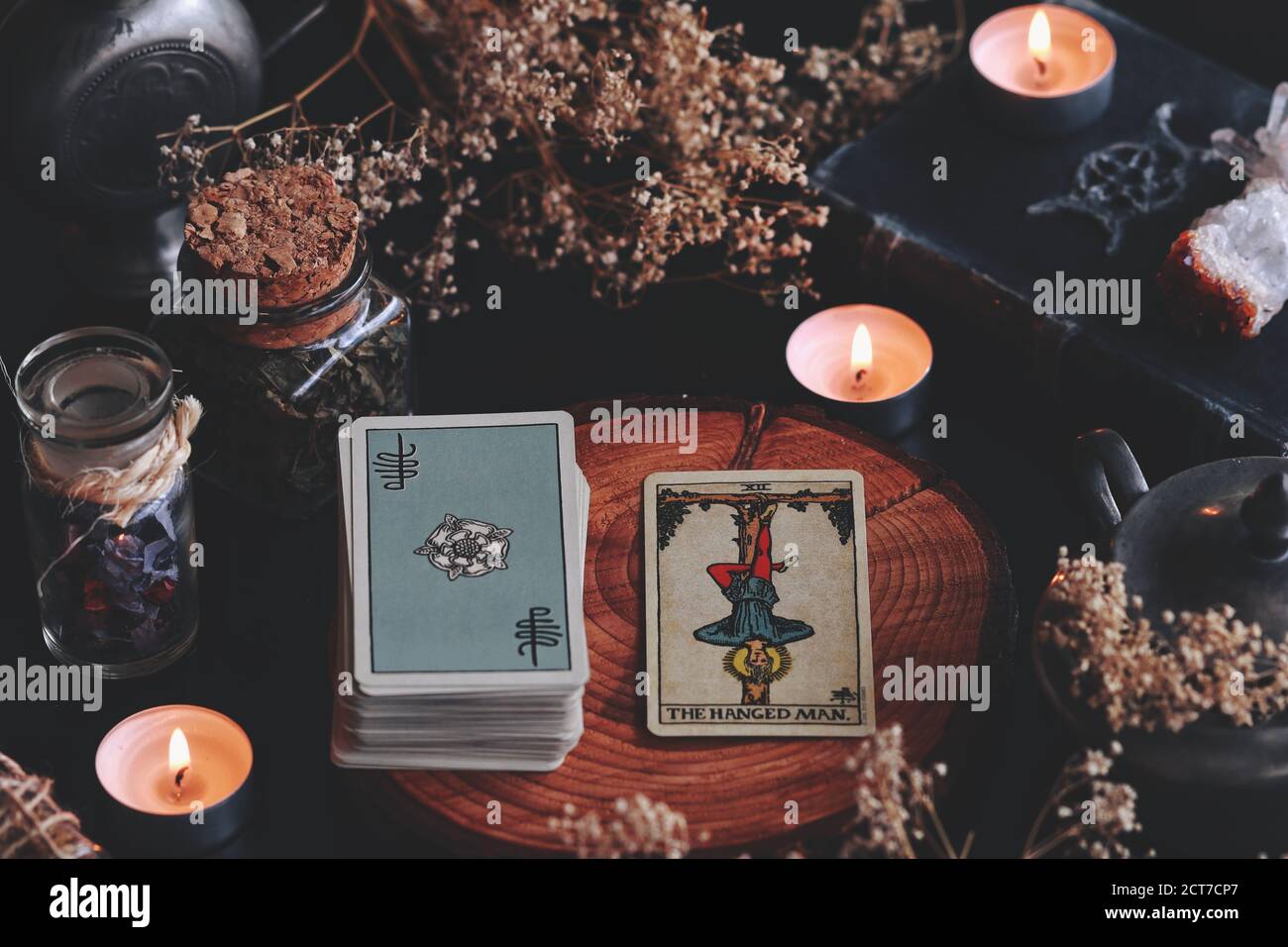 Die gehängte man Rider Waite Smith Mini Tarot Karte auf Holz Natur Display mit getrockneten Blumen und Kräutern. In einem Zentrum für Meditationszwecke dargestellt Stockfoto
