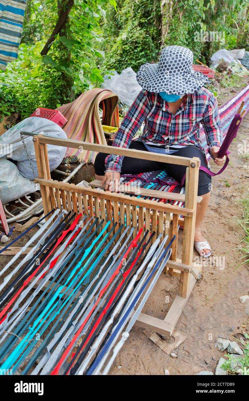 Frau, die am Webstuhl arbeitet und einen ausgestreckten Teppich (18 Meter) webt, der in kleinere Längen unterteilt werden soll, Bien Tien, Vietnam. Stockfoto