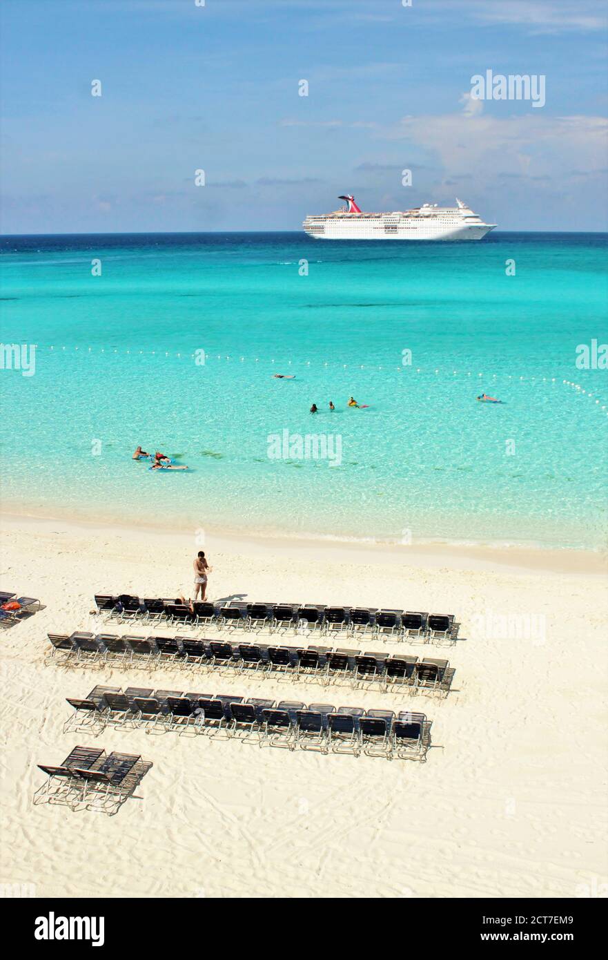 Strandliegen an einer wunderschönen blauen Küste mit einem Das Kreuzfahrtschiff dockte an der Küste an Stockfoto