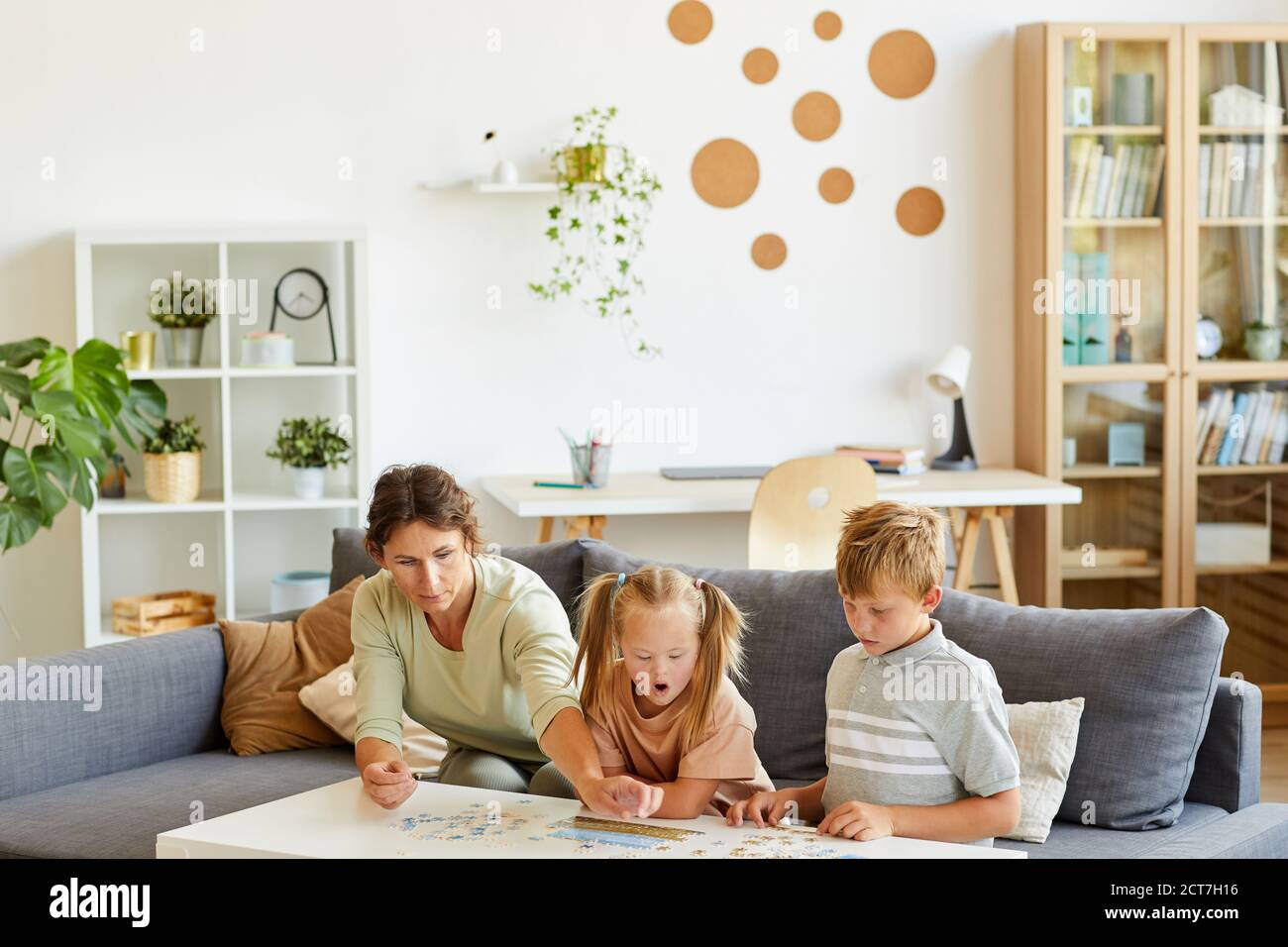 Weitwinkel-Porträt der liebevollen Familie mit besonderen Bedürfnissen Kind spielt mit Puzzles und Brettspiele zusammen zu Hause, kopieren Raum Stockfoto