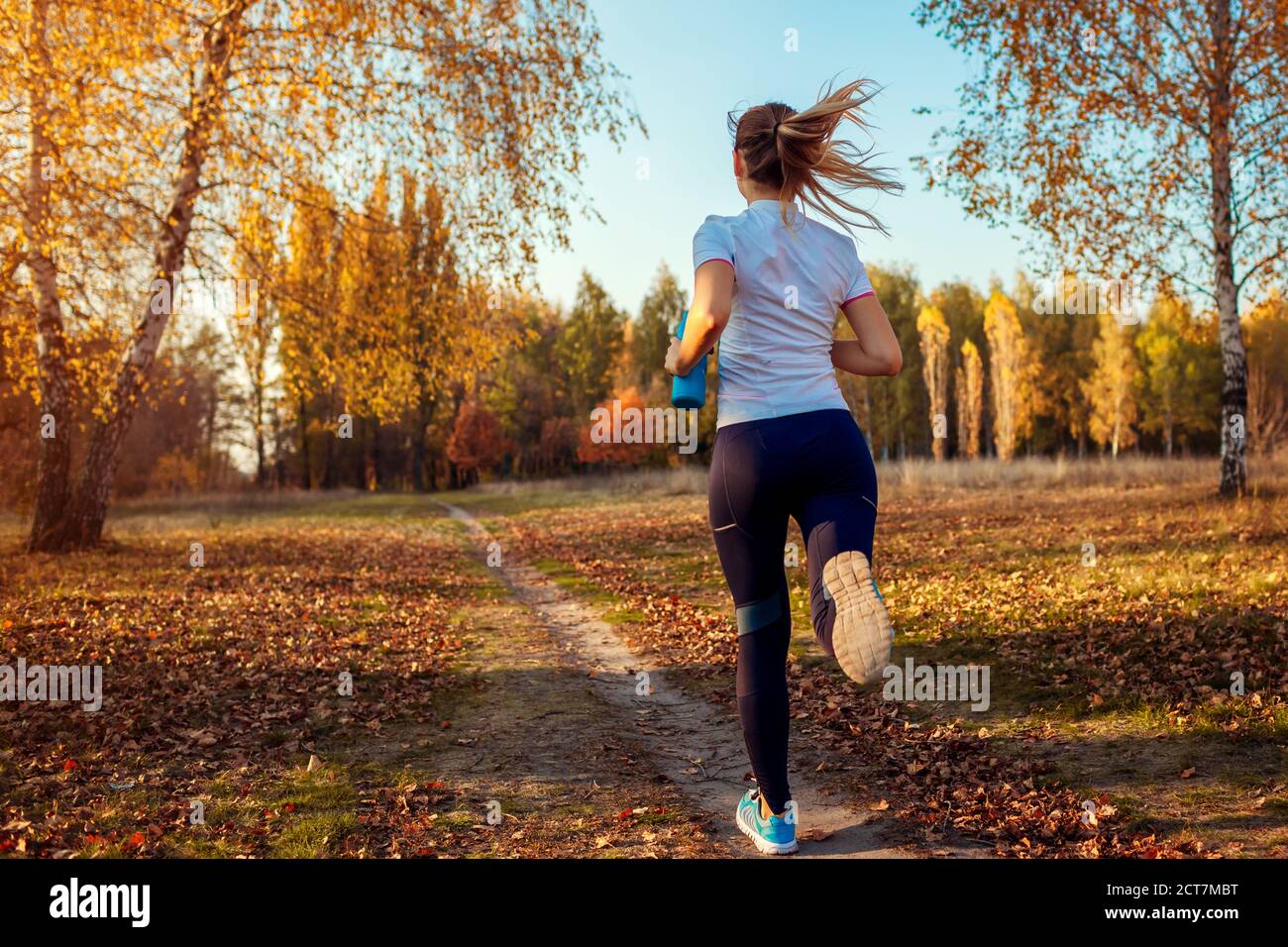 Läufertraining im Herbstpark. Junge Frau läuft bei Sonnenuntergang in sportlicher Kleidung. Aktiver Lebensstil. Rückansicht Stockfoto