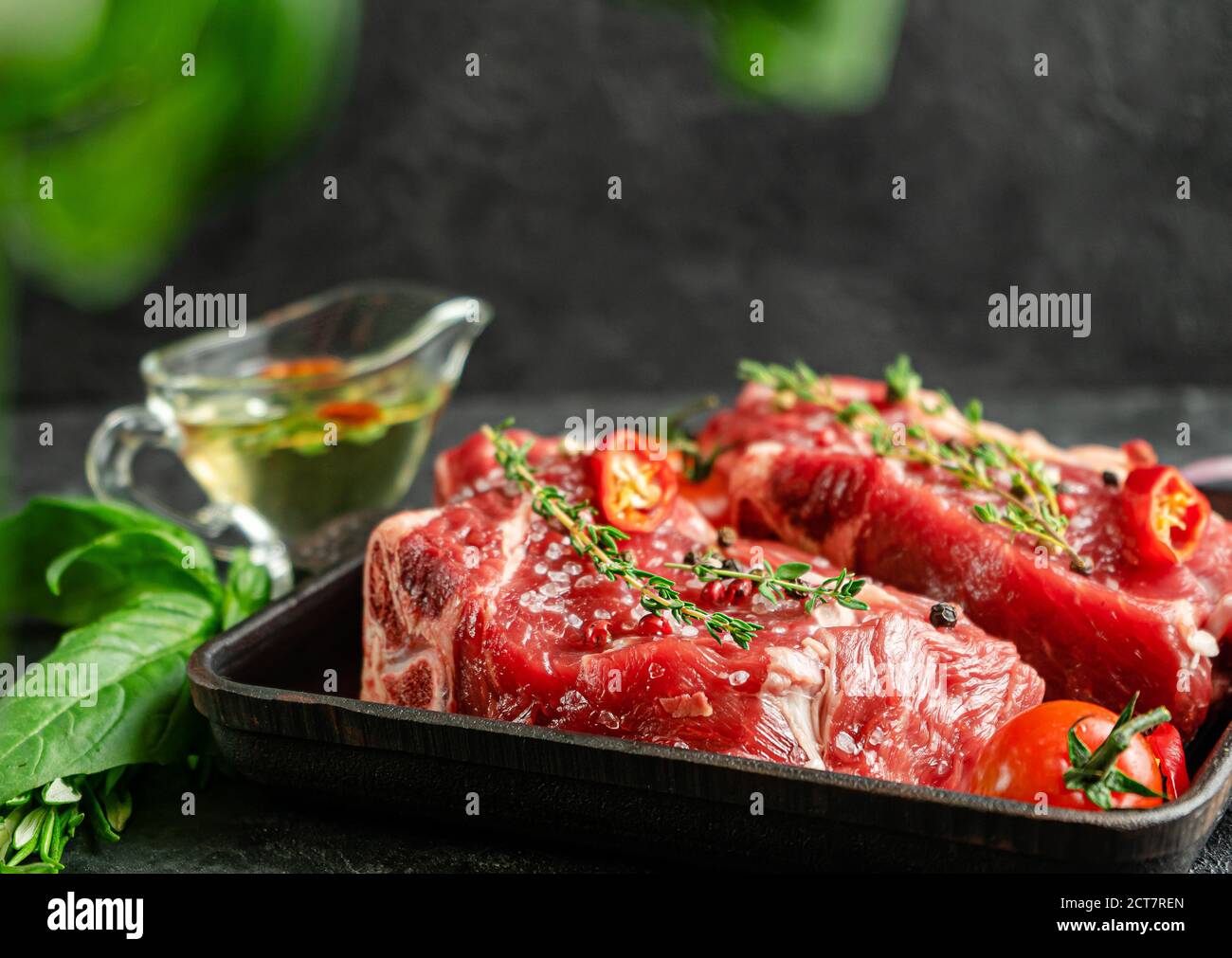 Rohe Kalbssteaks auf Grillpfanne mit Kräutern und würzigem Ölöl. Konzept für die Zubereitung von Speisen. Speicherplatz kopieren Stockfoto