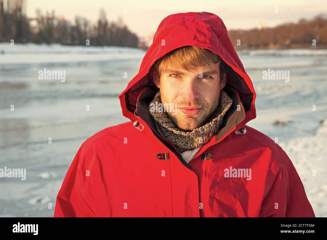 Frostig. Der Mensch genießt verschneite Landschaft bei Sonnenuntergang. Reise- und Expeditionkonzept. Mann in roter Parka. Winter männlich. Warme Kleidung für kaltes Klima. Wettervorhersage. Mensch und Natur. Stockfoto