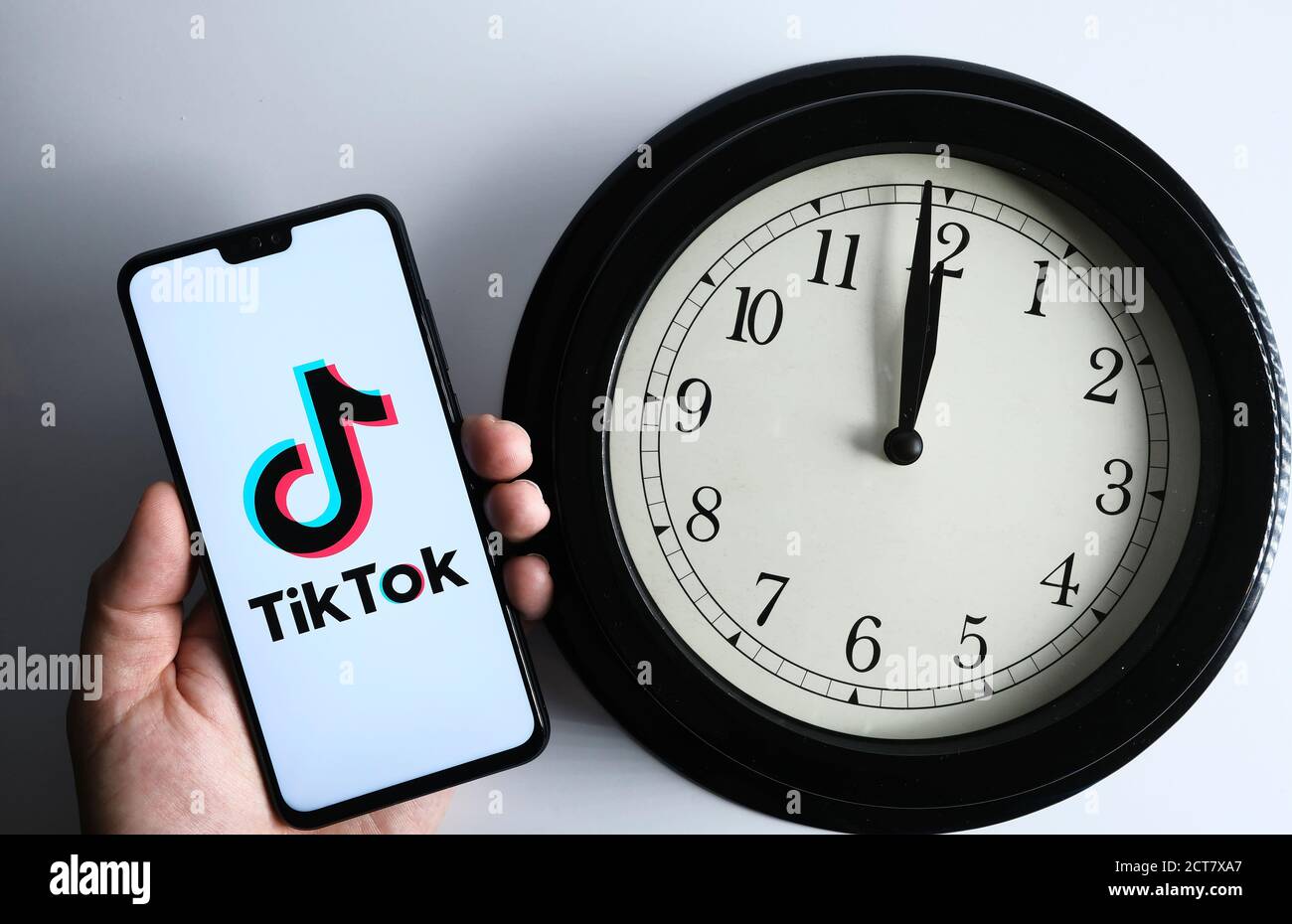 Stafford / UK - September 21 2020: TikTok und die Uhr, Konzept. TikTok-Logo auf dem Smartphone in der Hand halten und die analoge Uhr daneben. Stockfoto