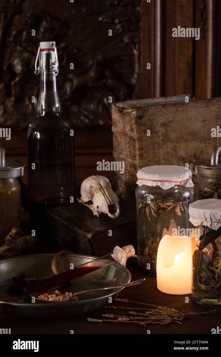 Unheimliche Hexenküche mit vielen Zutaten für einen Trank Und alte grausame Gläser dunkel mit nur Kerzenlicht für Halloween Stockfoto