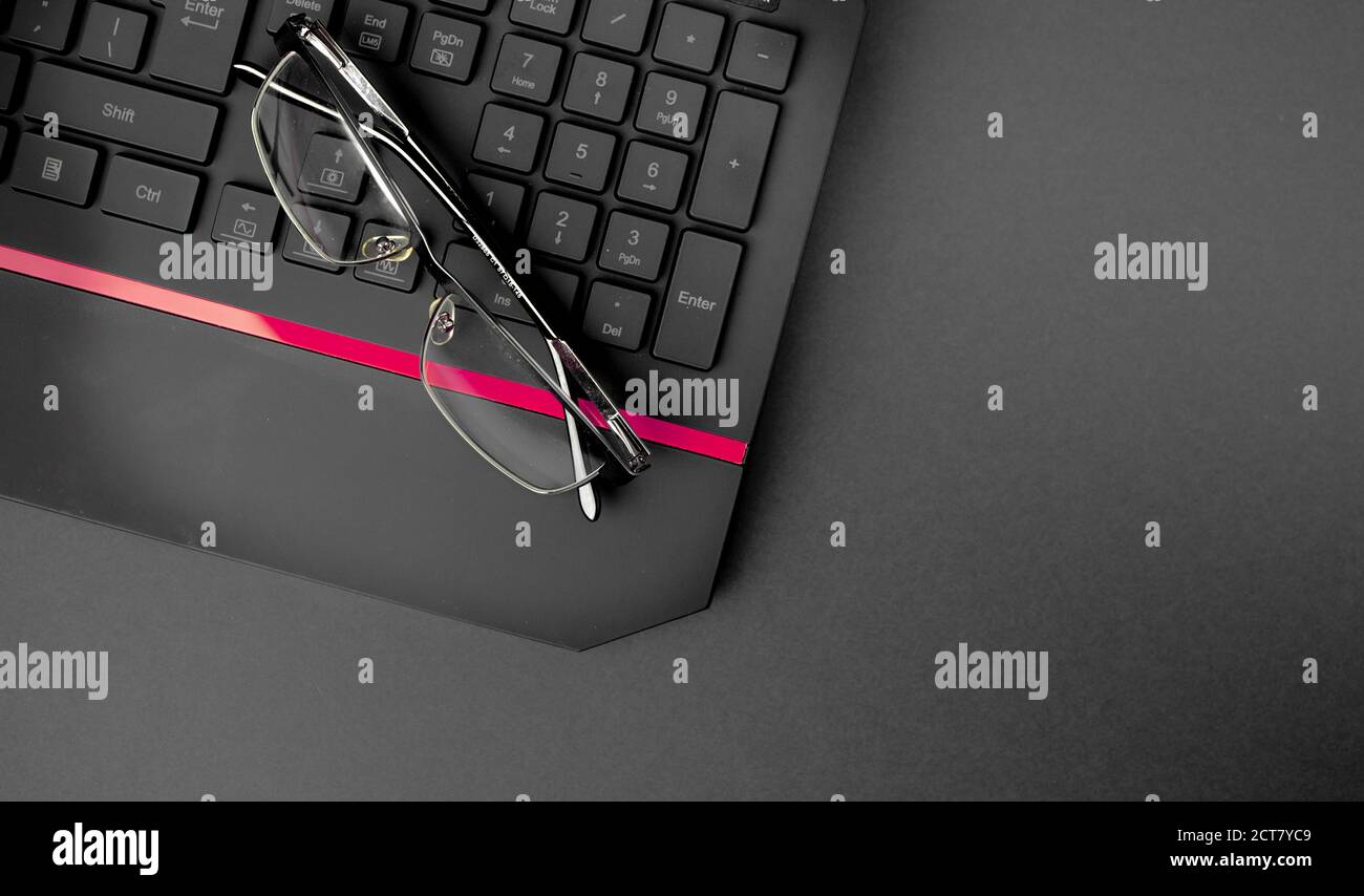 Nahaufnahme der schwarzen Tastatur mit Brille auf dem Tisch. Büro, Arbeiten von zu Hause Konzept Stockfoto