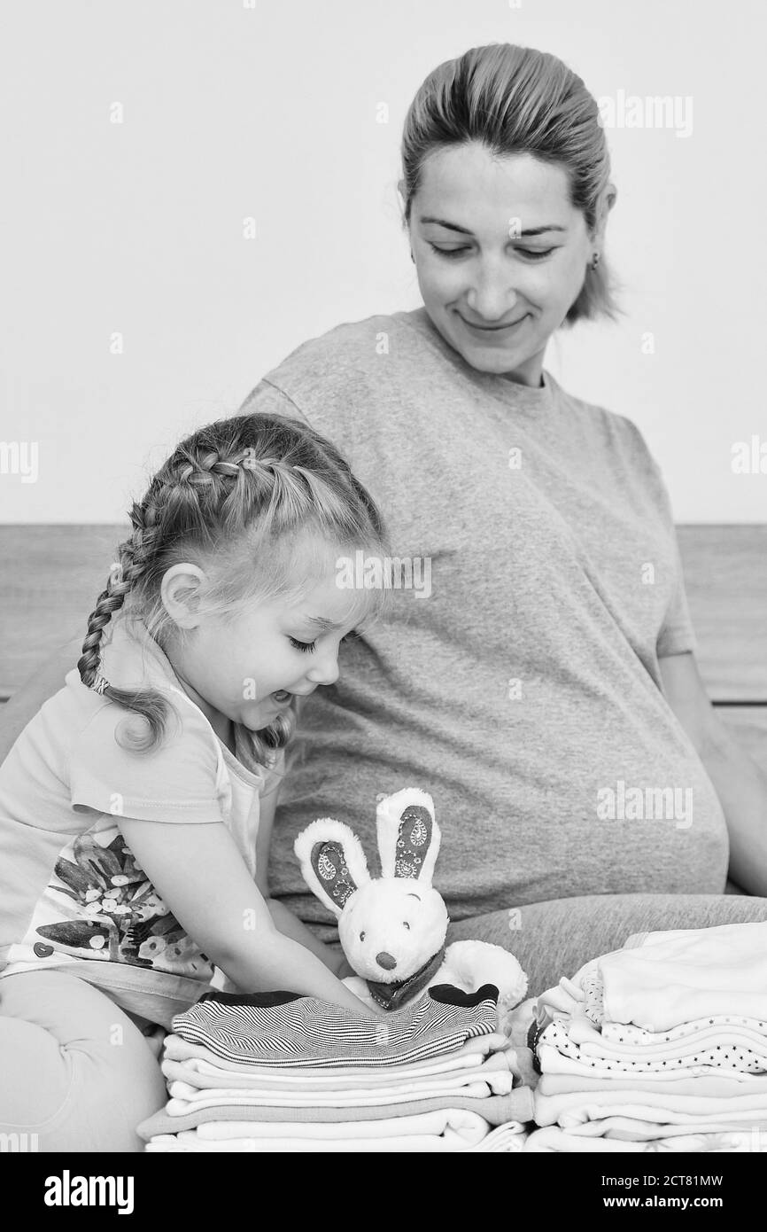 Mutter und Tochter bereiten Kleidung für einen neugeborenen Jungen vor Stockfoto