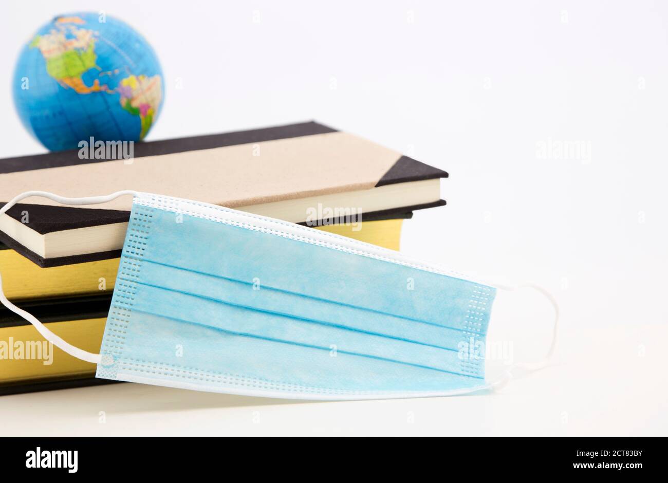 Bücher, Masken und Globussymbole spiegeln den weltweiten Bedarf an wissenschaftlicher Forschung und persönlicher Schutzausrüstung wider Stockfoto