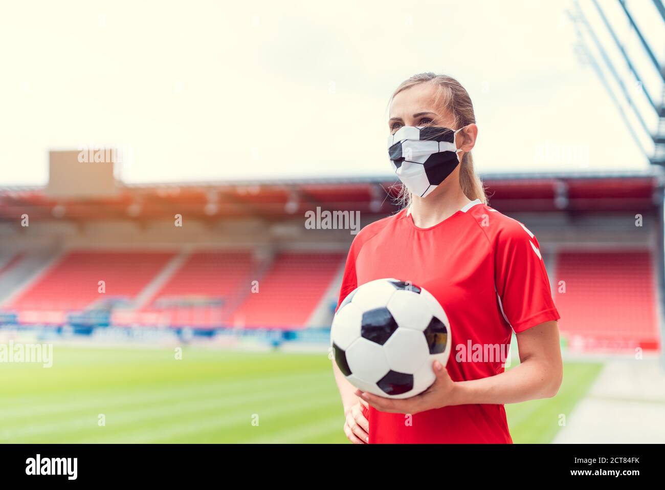 Frau Fußballspielerin trägt Gesichtsmaske im leeren Stadion Stockfoto